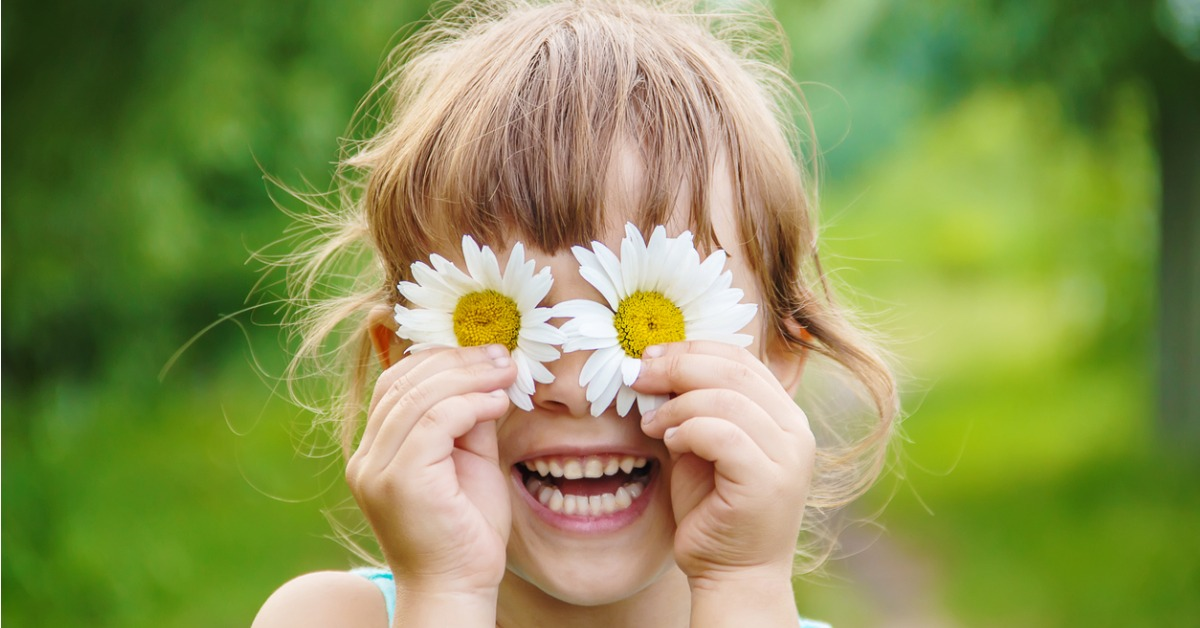 A little girl with daisies over her eyes