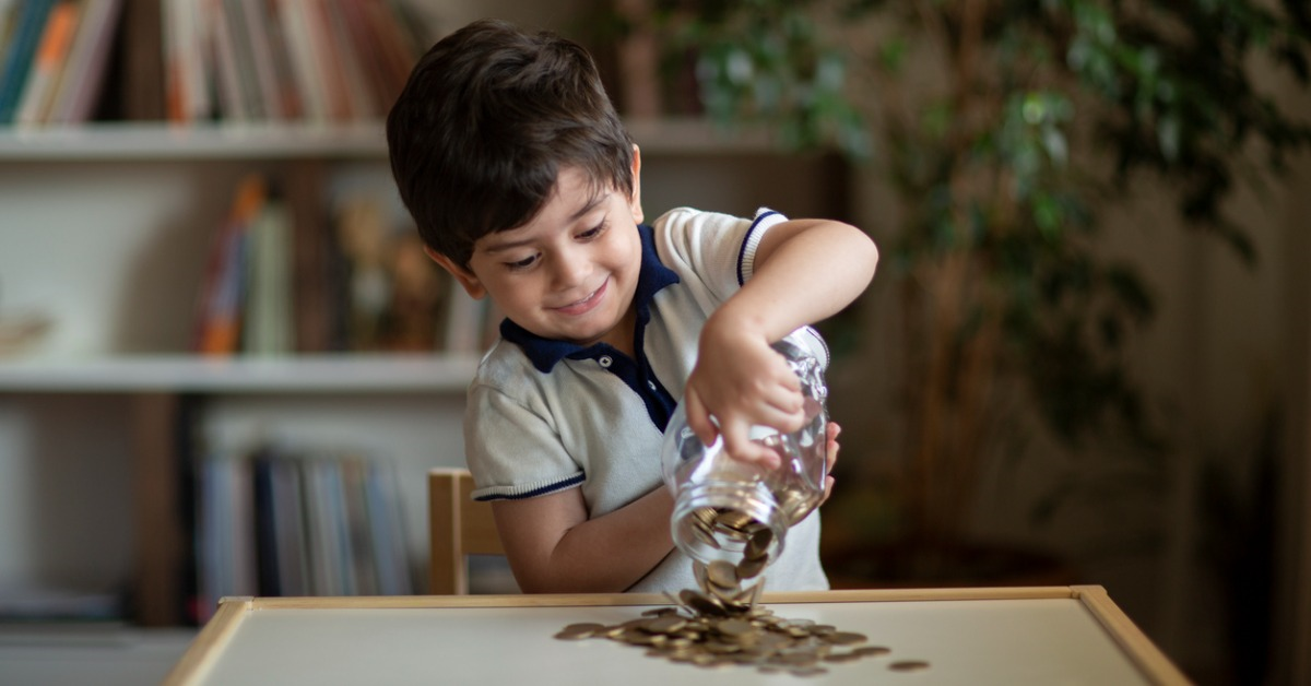 A boy pouring money out of a jar onto a table